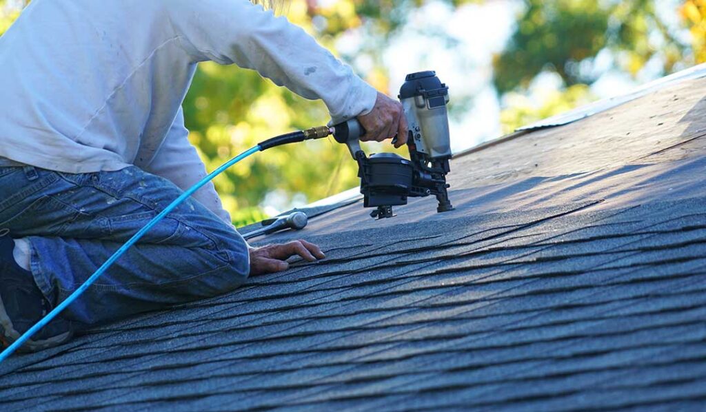 Homeowner inspecting roof shingles and gutters from the ground during early spring.